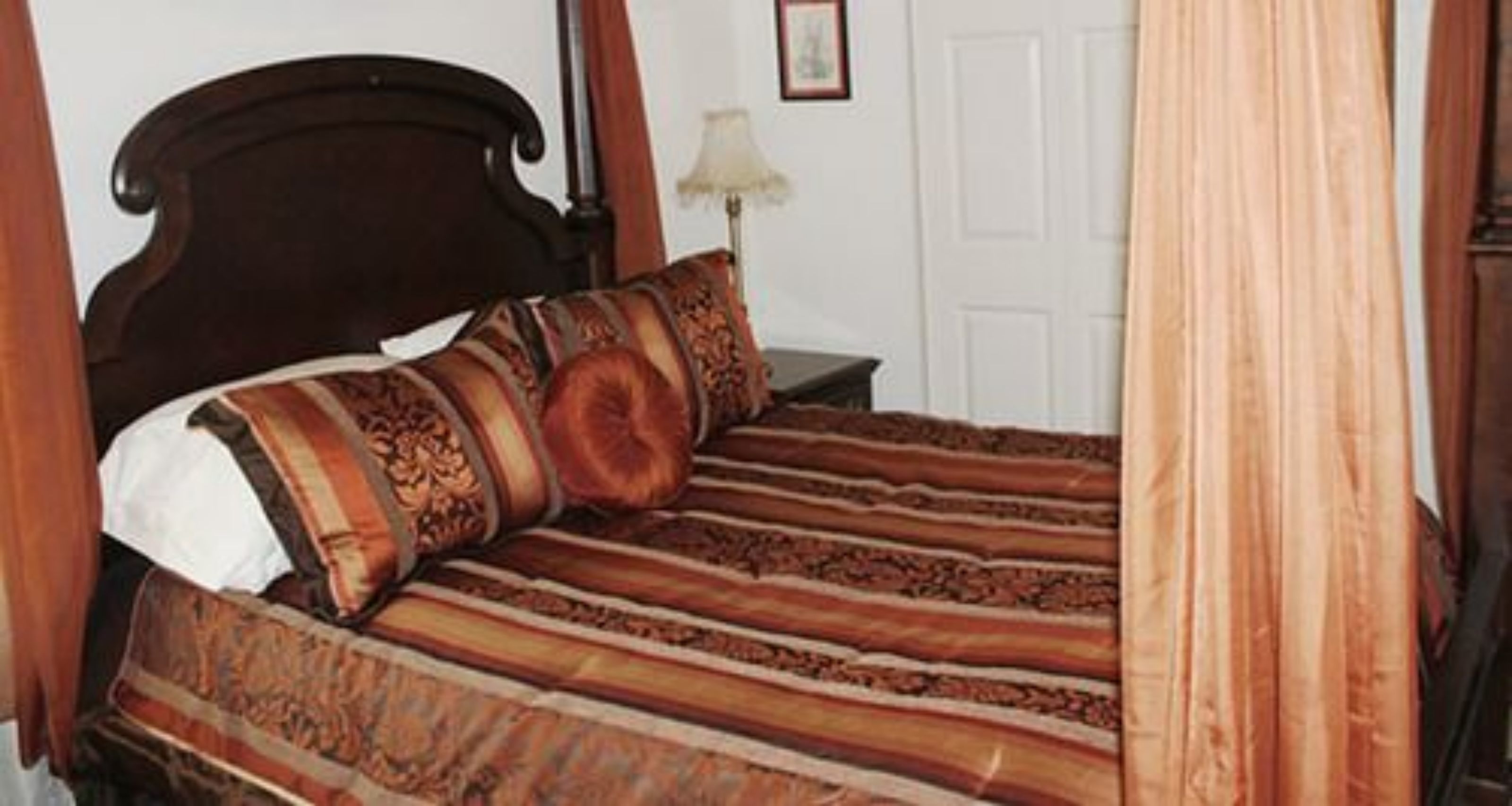 A bed with a patterned bedspread, a wooden headboard, and a bedside lamp.