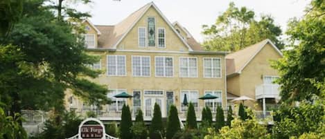A large, two-story building with a symmetrical facade, multiple windows, and a well-maintained lawn with trees.