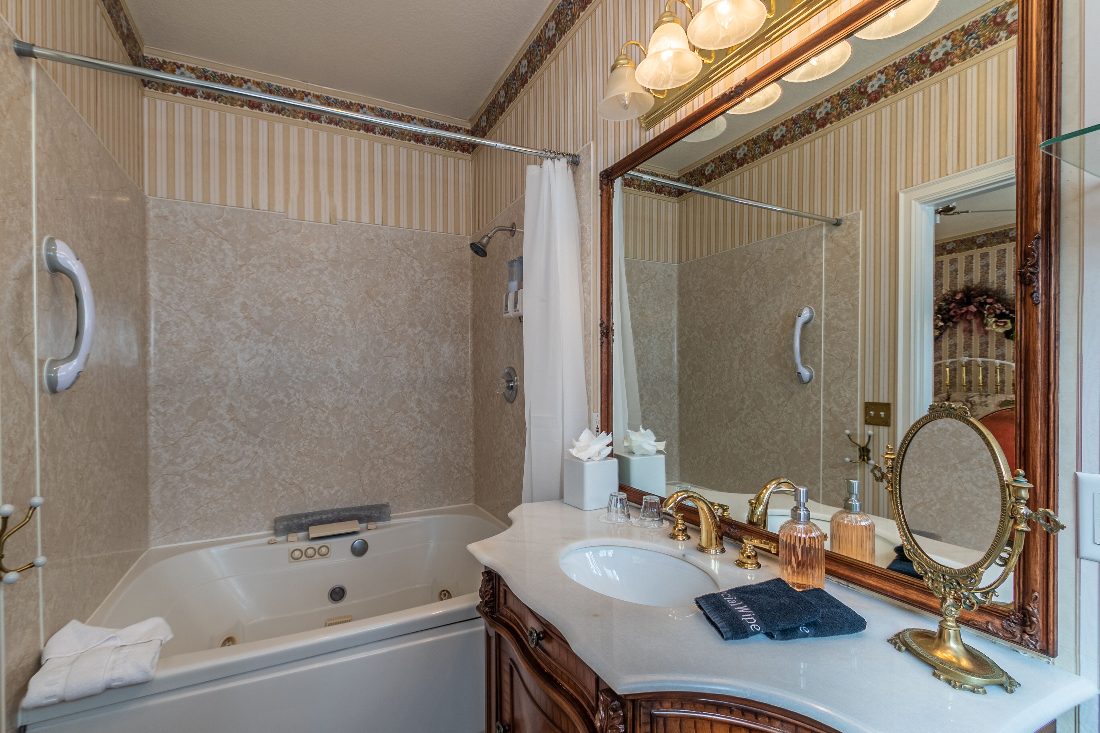 Une salle de bain comprenant une baignoire, un lavabo, un meuble-lavabo avec un miroir et un espace douche.