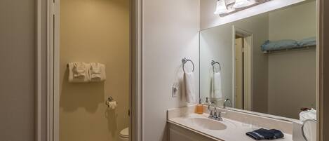 Un baño con lavabo blanco, espejo y toallero.