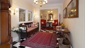 A traditional room with a checkered floor, a red rug, a wooden bench, a table with a vase of flowers, and a mirror on the wall. - North Bridge Inn (Concord)