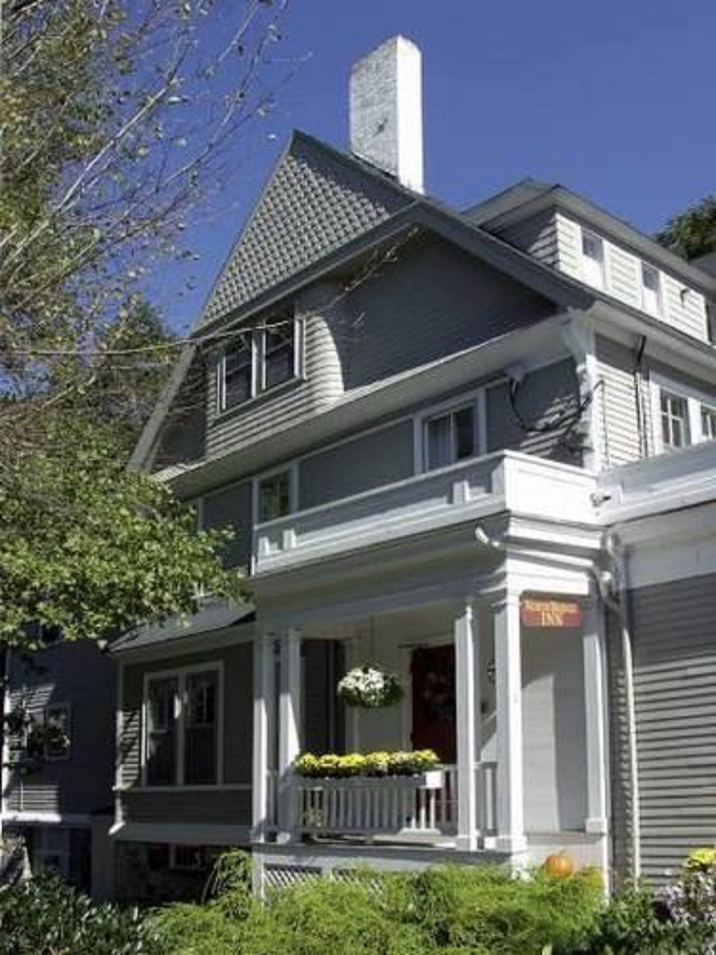 A two-story house with a front porch, a chimney, and a garage door.