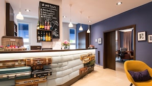 Een hotel receptie met een balie waarop verschillende koffers staan, een schoolbordmenu en een gele stoel.