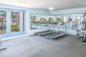 Een fitnessruimte met loopbanden, trainingsfietsen en een rookvrij bord.