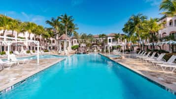 A swimming pool with lounge chairs and palm trees.