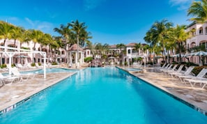 A swimming pool with lounge chairs and palm trees.