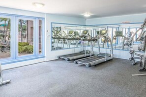 Un gimnasio con cintas de correr, bicicletas estáticas y pesas, amplias ventanas y un cartel de 'NO FUMAR'.