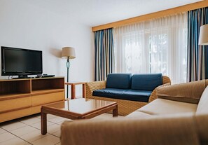 Una sala de estar con televisor, sofá y mesa de centro.