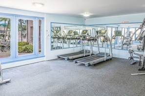 A gym with treadmills, exercise bikes, and a no-smoking sign.