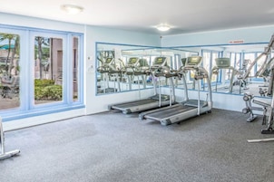 Un gimnasio con cintas de correr, bicicletas estáticas y un cartel de prohibido fumar.