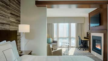Una habitación de hotel con cama, escritorio, silla, televisión y chimenea.