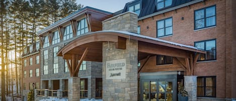 A multi-story hotel with a stone facade, large windows, and a covered entrance.