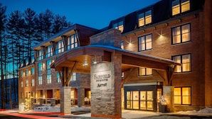 Un hotel de varios pisos con fachada de piedra, ventanas grandes y un cartel luminoso.