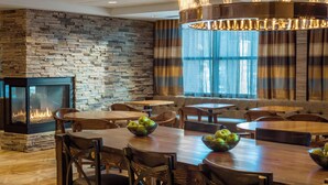 Un restaurante acogedor con pared de piedra, chimenea y mesas de madera con cuencos de fruta.