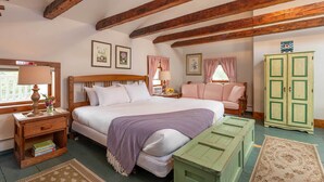 Une chambre à coucher avec un lit en bois, une table de chevet avec une lampe, une commode verte et un banc vert.