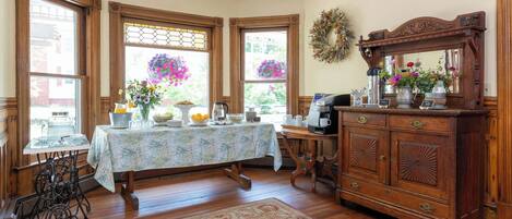 A dining area with a table set for four, a vintage sewing machine, a wooden cabinet, and a ceiling fan.