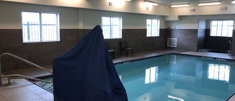 An indoor swimming pool with a covered area, tiled walls, and windows.
