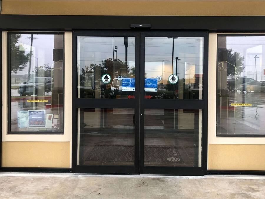 Una entrada de edificio con puertas automáticas y ventanas de vidrio.
