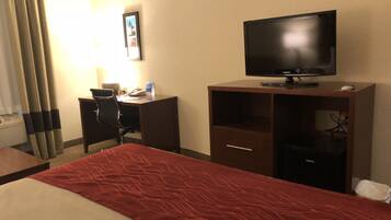 Une chambre d’hôtel comprenant un lit, un bureau avec une chaise, une télévision et un tableau accroché au mur.