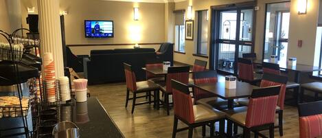 Un restaurante con zona de bar, mesas y una pantalla mostrando un programa.
