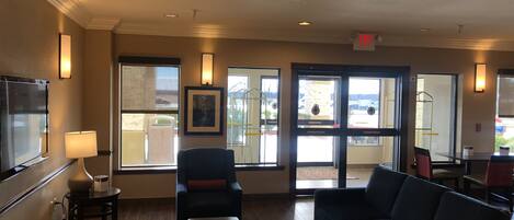 A hotel lobby with a seating area, a TV, and a view of the outside.