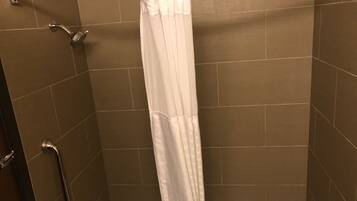 Ducha con cortina blanca, cabezal de ducha de mano y barra de apoyo.