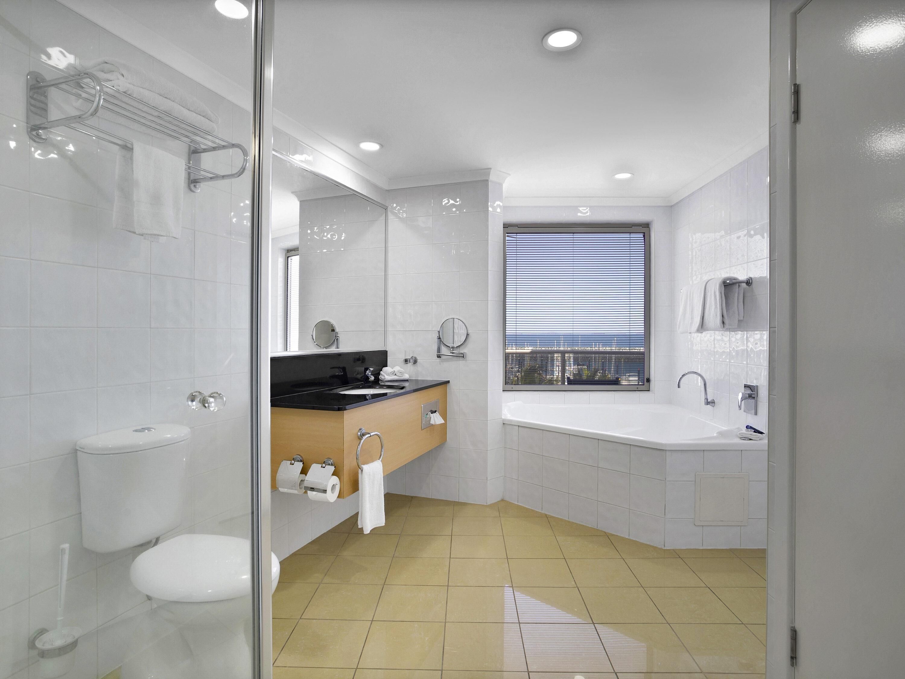 A modern bathroom with a toilet, sink, vanity, and bathtub.