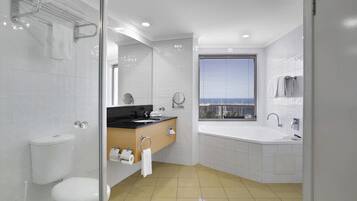 A modern bathroom with a toilet, sink, vanity, and bathtub.