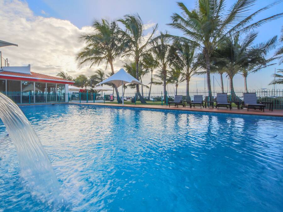 Een buitenzwembad, ligstoelen bij het zwembad