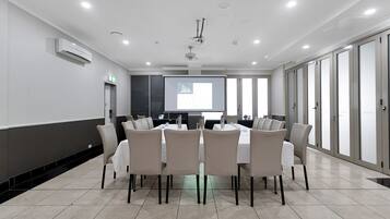 A conference room with a projector screen displaying a graph, a whiteboard, and a table with chairs.