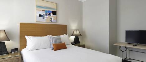 A hotel room with a bed, two bedside tables, a television, and a painting on the wall.