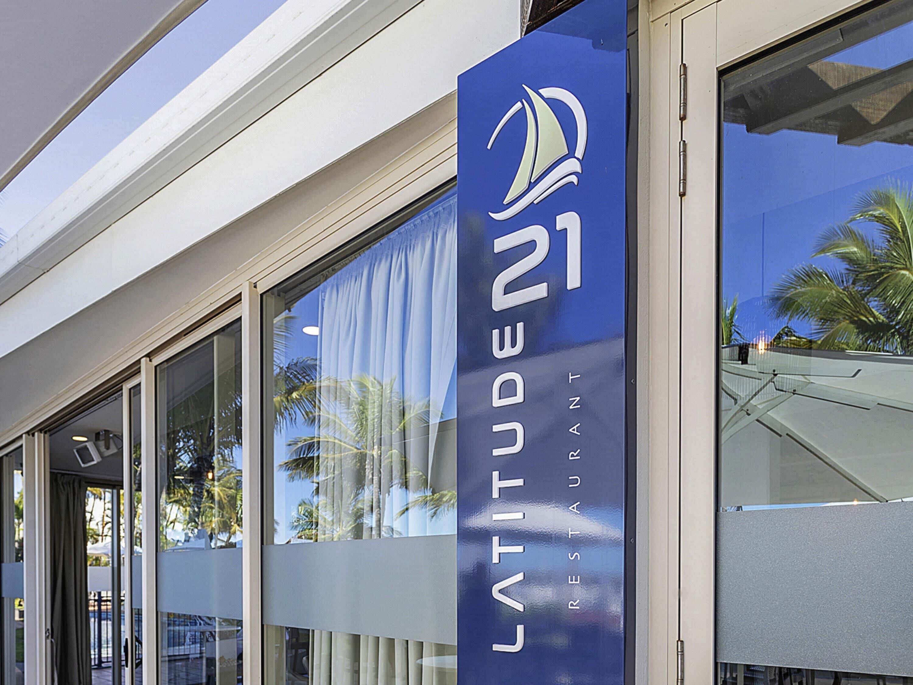 Um edifício com uma grande janela e uma placa com a inscrição 'LATITUDE 21 RESTAUNT'.