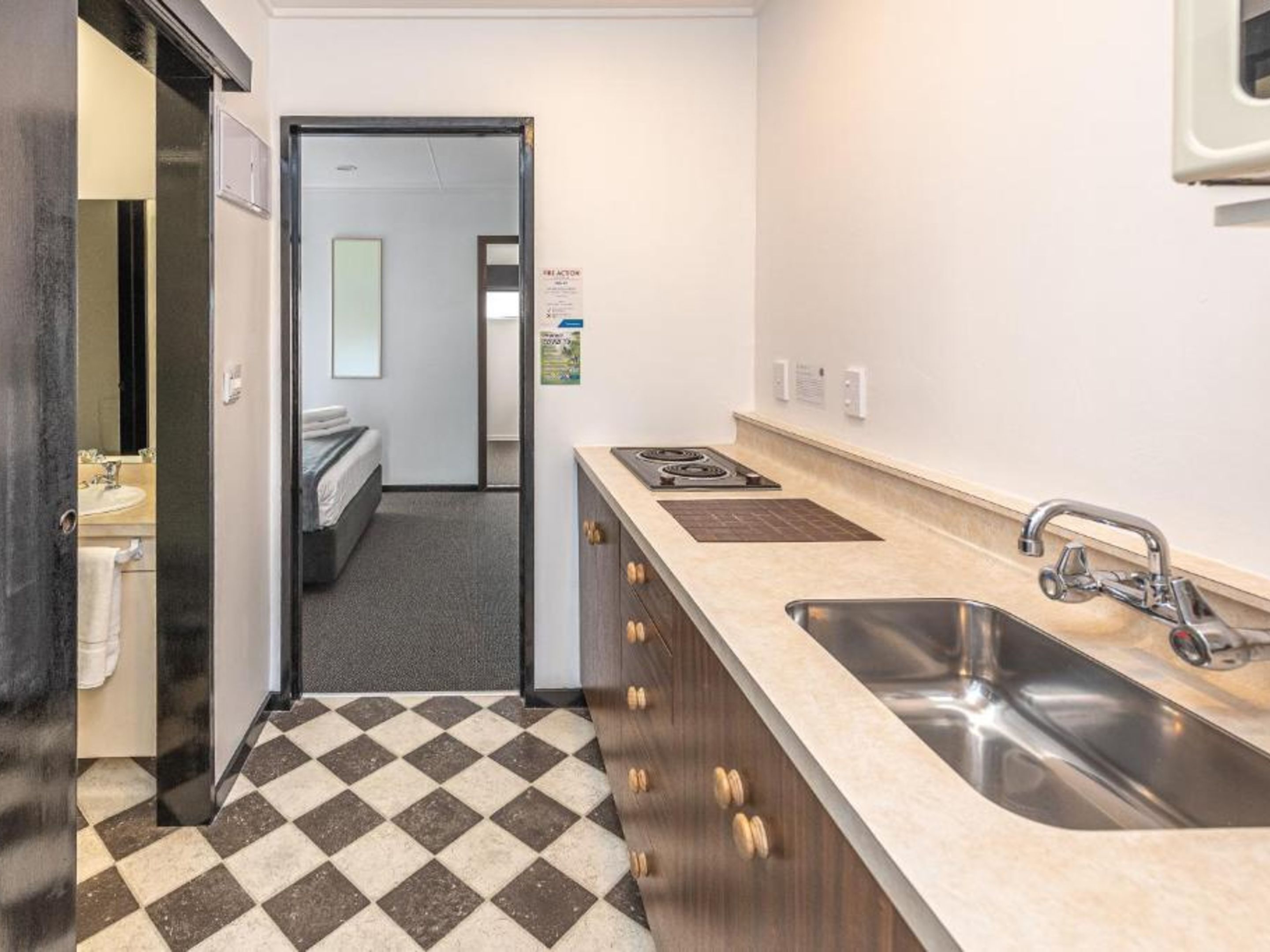 A compact kitchen with a sink, stove, and a checkered floor.