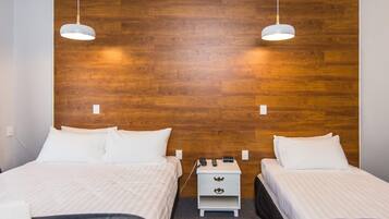 Habitación de hotel con dos camas, cabecero de madera, ropa de cama blanca, mesitas de noche con lámparas y suelo cubierto de alfombra.