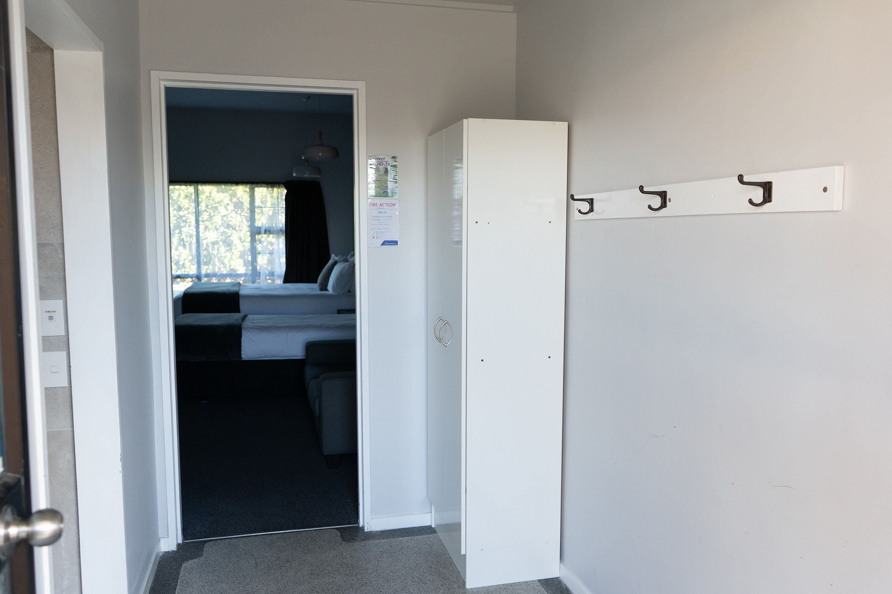 Ein Flur mit einer weißen Tür, die zu einem Schlafzimmer führt. An der Wand hängt ein Kleiderständer mit Haken.