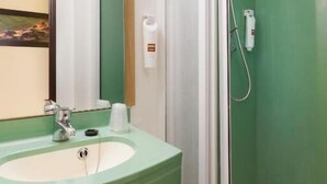 Une salle de bain avec un lavabo, un miroir et une douche, le tout de couleur verte.