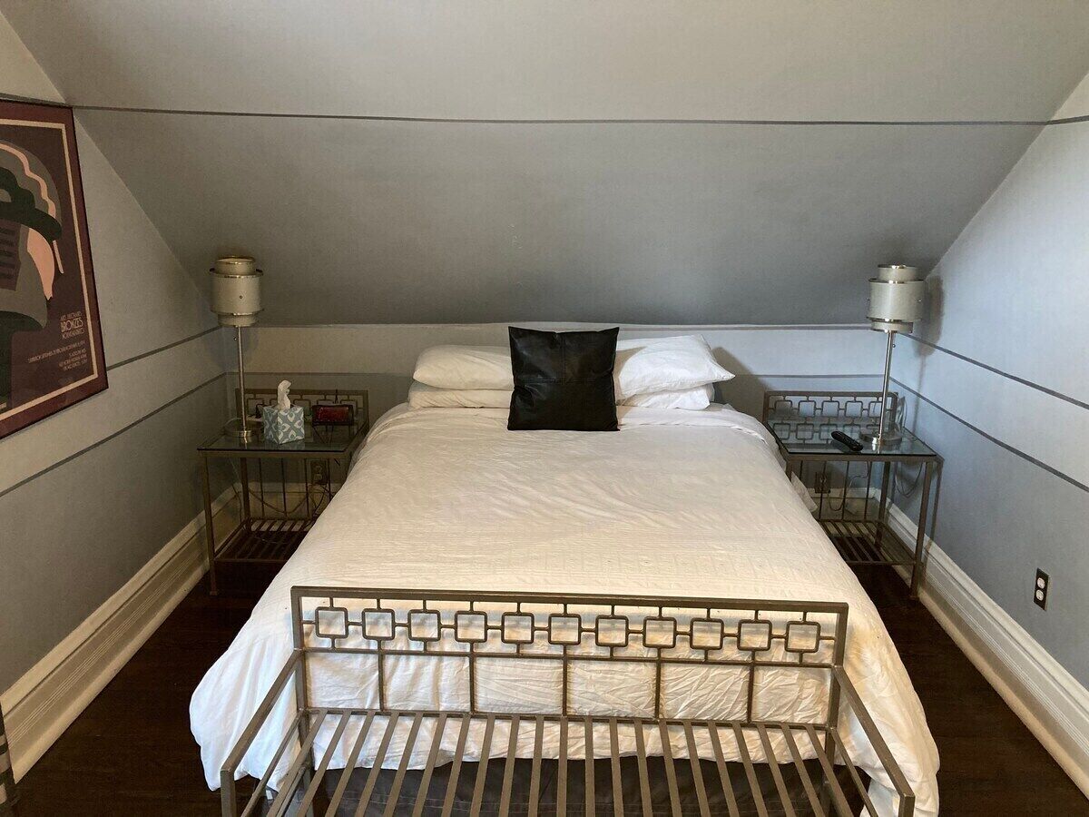 A neatly made bed with a metal frame, two bedside tables with lamps, and a framed picture on the wall.