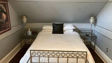 A neatly made bed with a metal frame, two bedside tables with lamps, and a framed picture on the wall.