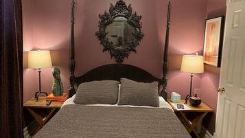 Un dormitorio con cama con dosel, dos mesitas de noche, un espejo y una puerta.