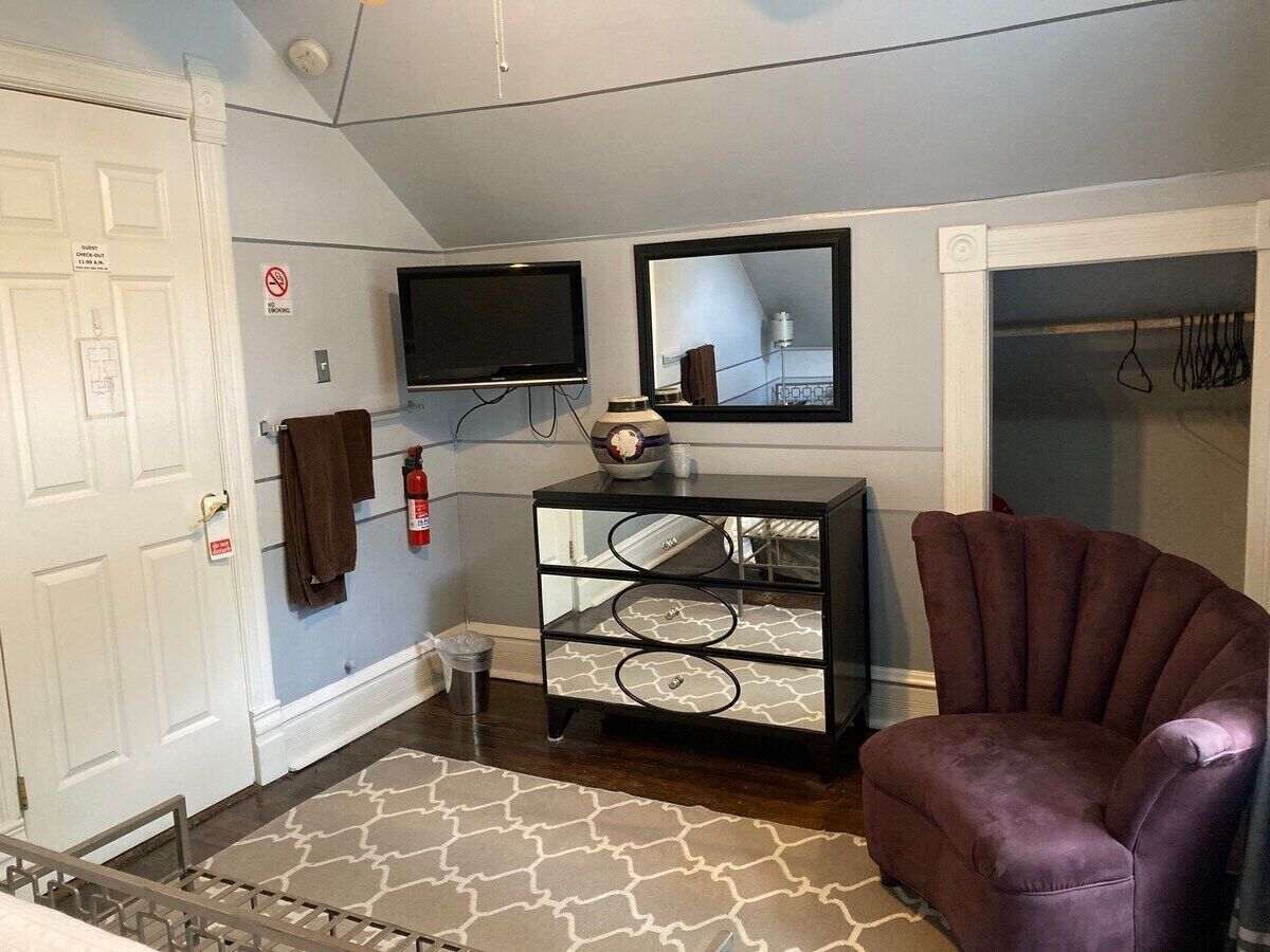 Une pièce comprenant un lit, une commode, une chaise, un téléviseur et un miroir.