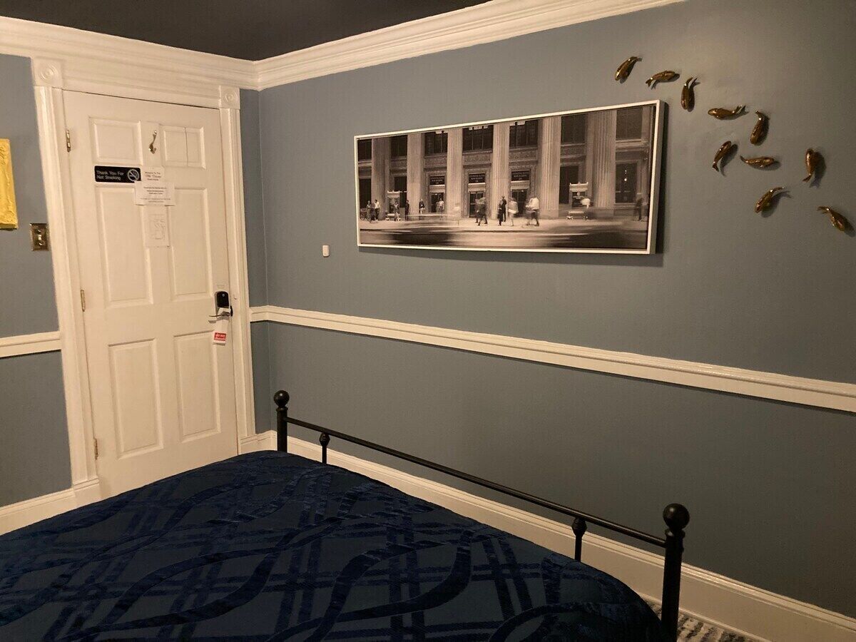 A bedroom with a bed, a door, and a framed photograph on the wall.