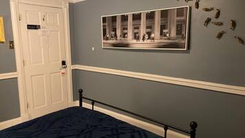 A bedroom with a bed, a door, and a framed photograph on the wall.