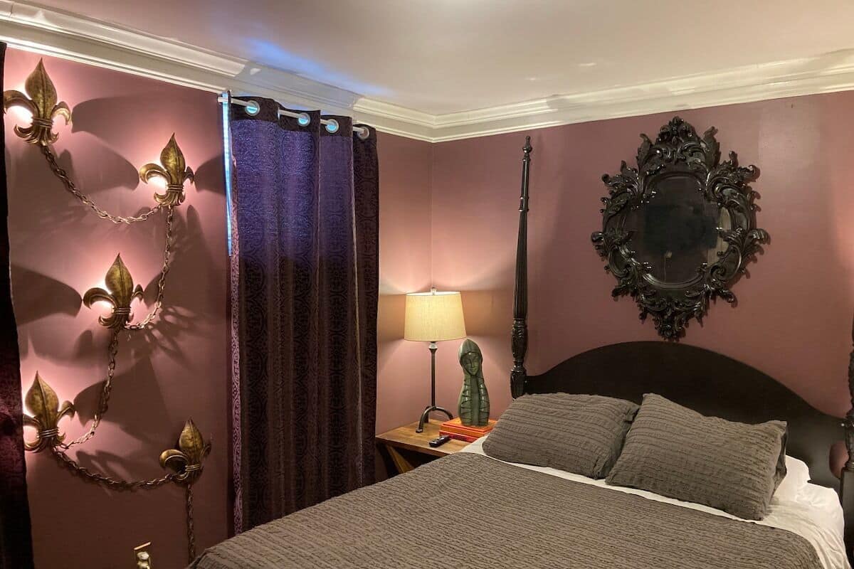 A bedroom with a bed, a nightstand, a lamp, and a mirror.
