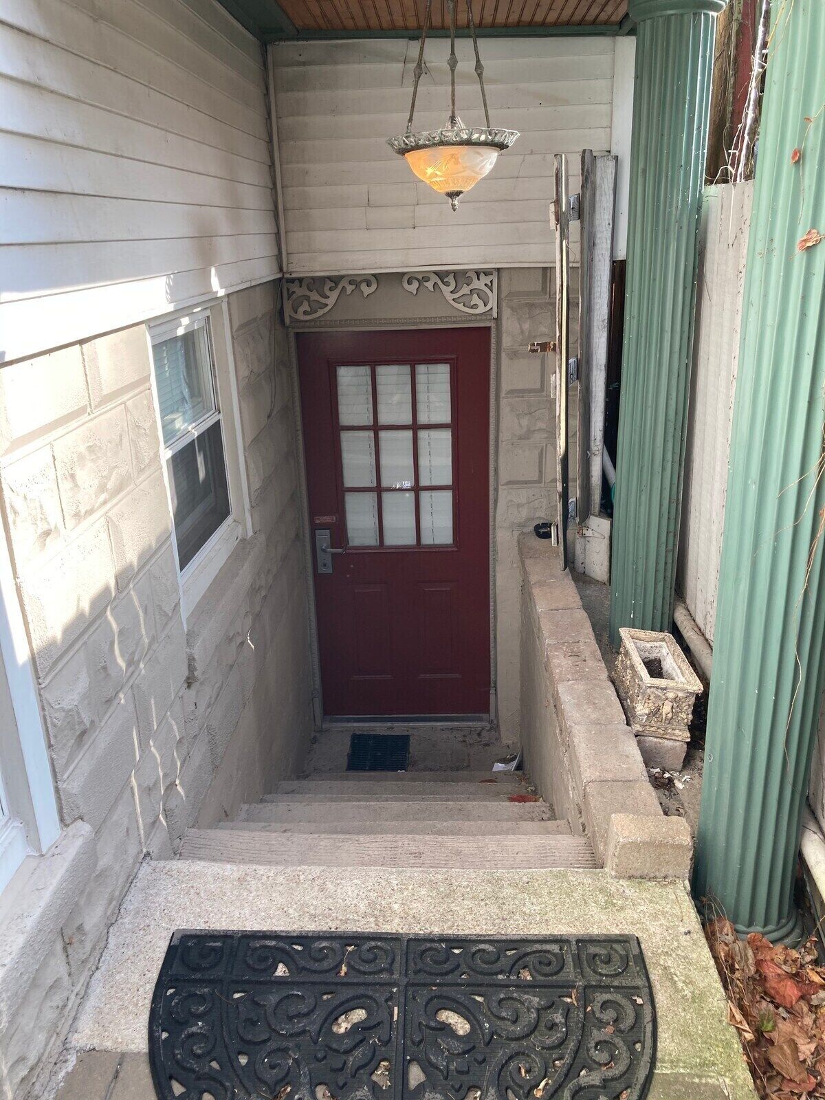 A narrow entrance with a red door, a small window, and a decorative metal gate.
