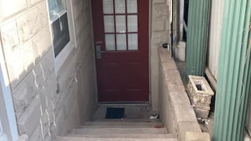 A narrow entrance with a red door, a small window, and a decorative metal gate.