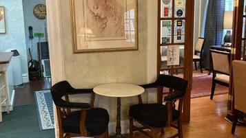 Un comedor con una mesa redonda y cuatro sillas, una obra de arte grande enmarcadas en la pared, y un tapete estampado en el suelo.