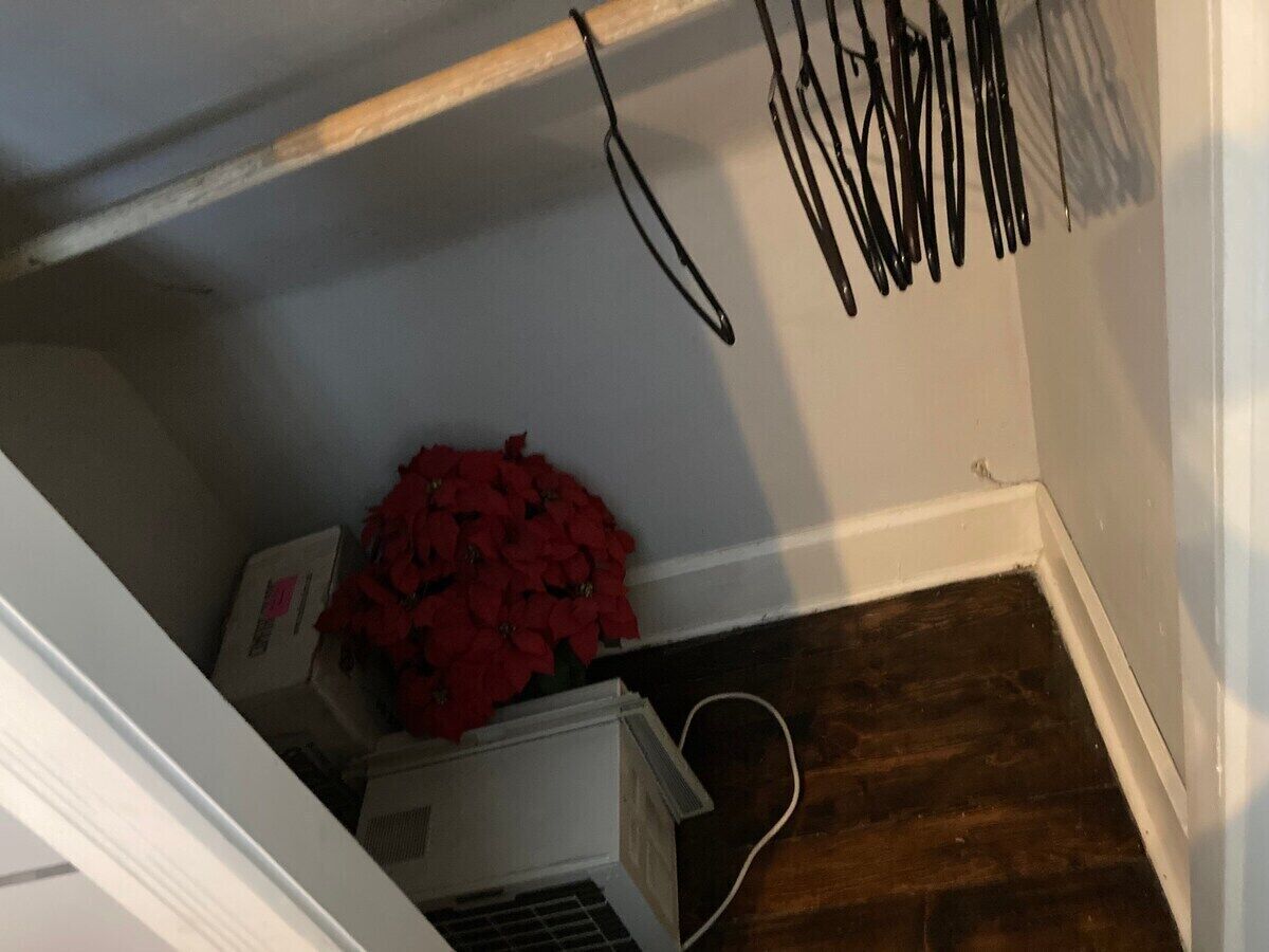 Un escalier étroit avec un mur blanc, une main courante en bois et une plinthe blanche.