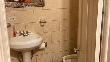 A small bathroom with a pedestal sink, a toilet, and a trash can.