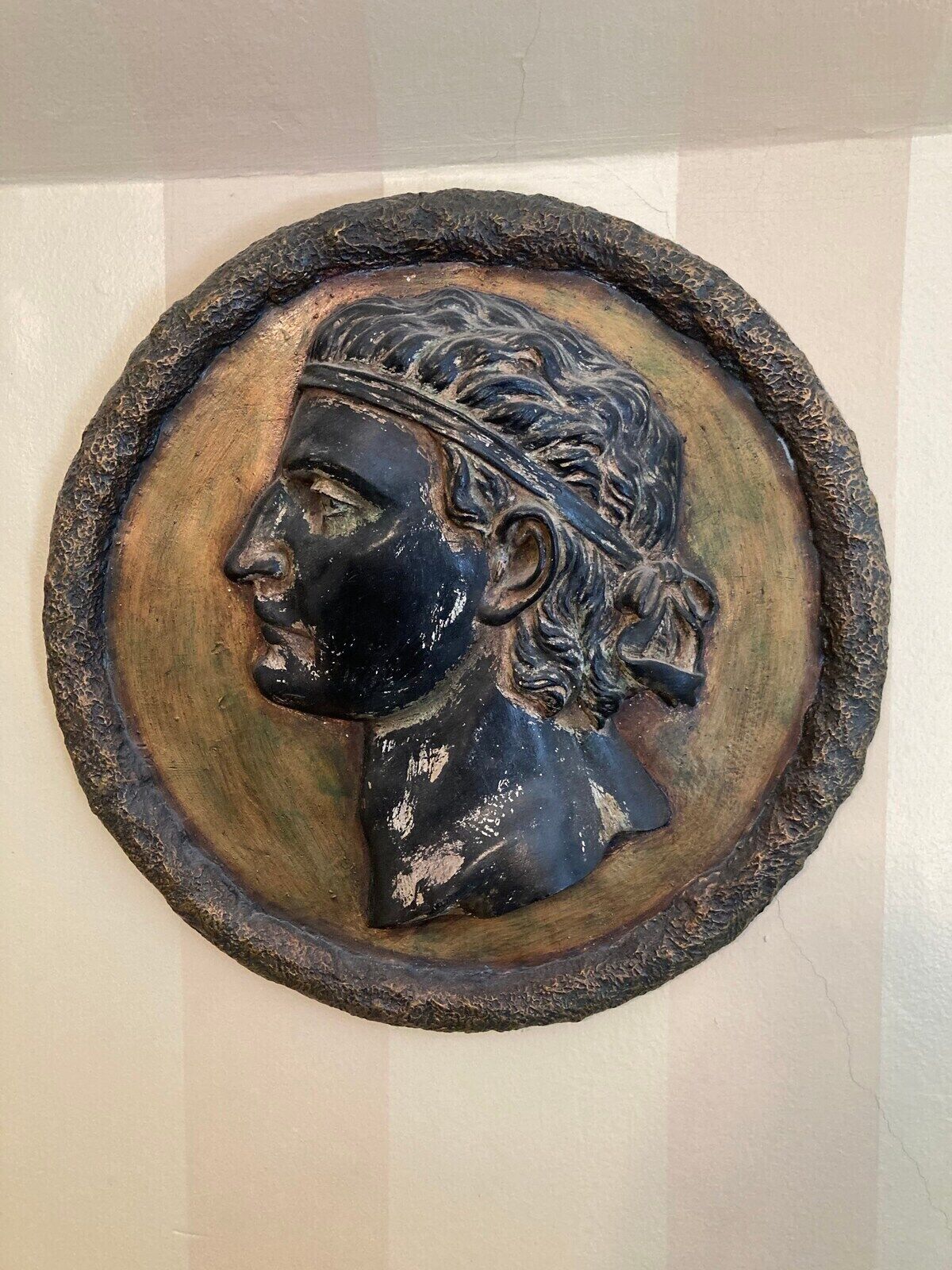 A circular wooden plaque with a carved profile of a person.