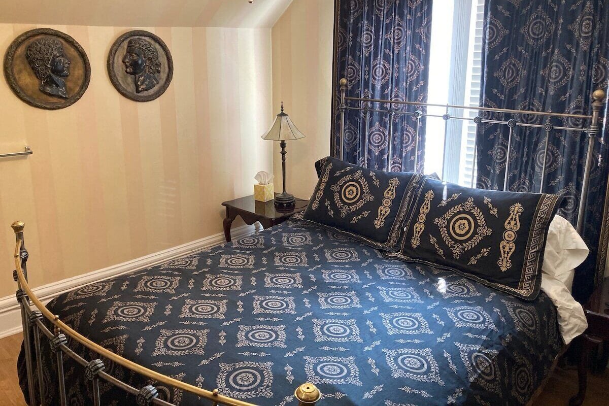 A bedroom with a bed, a nightstand, a lamp, and two wall-mounted decorative plates.